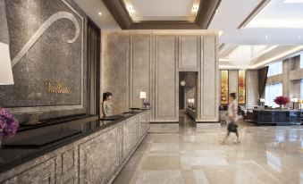 a woman is standing at the front desk of a hotel , possibly checking in or checking in at Hotel Valletta