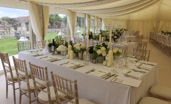 a long dining table covered with white tablecloths and adorned with flowers , surrounded by chairs at The Durham Ox