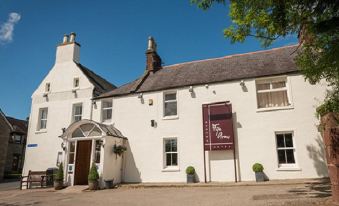 a white building with a red banner hanging from the top and windows that offer views of trees and a clear blue sky at Fife Arms Hotel