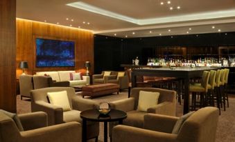 a modern lounge area with comfortable seating , a bar , and a large screen displaying drinks at The Retreat