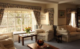 a cozy living room with a large window , two couches , and a coffee table in the center at Lydgate House Hotel