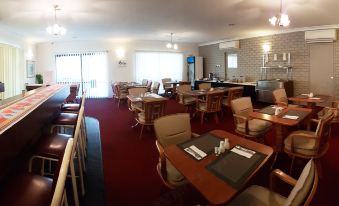 a dining area with tables and chairs , a counter with drinks , and a large window at Tropic Coast Motel