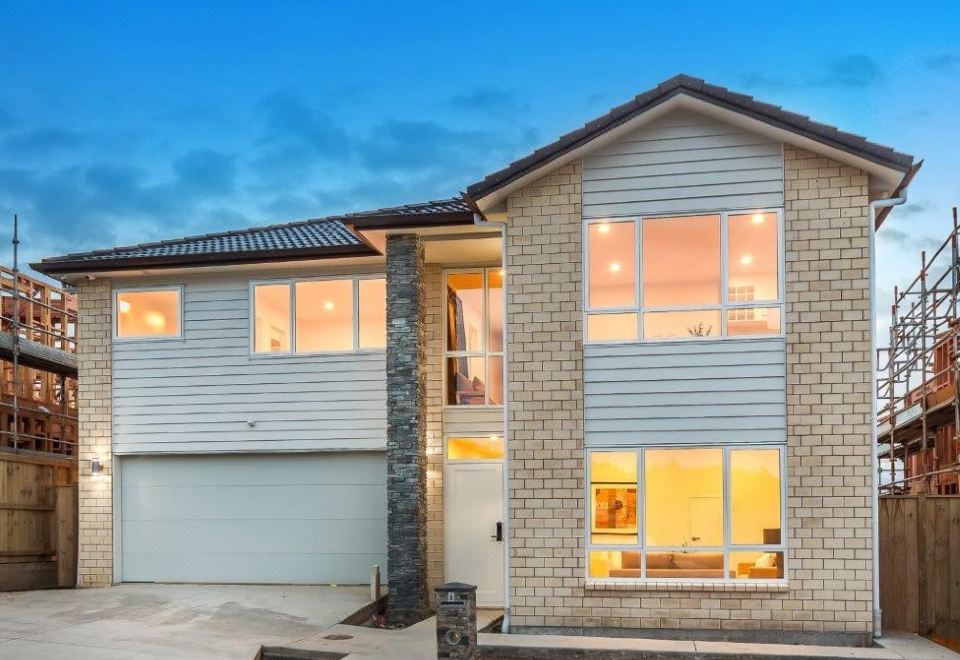 a modern house with two floors , a garage , and large windows under a blue sky at Flat Bush Holiday Accomodation