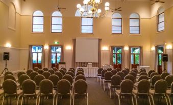 a large conference room with multiple rows of chairs arranged in front of a projector screen at Cairns Colonial Club Resort