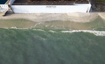 aerial view of a beach with a hotel next to the ocean , surrounded by sand and water at Hompton Hotel by The Beach