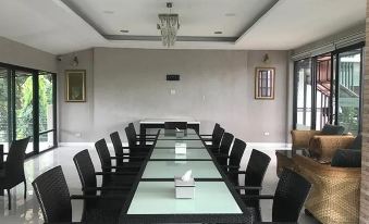 a long table with black chairs and a chandelier hangs from the ceiling in a room at The Sept Korat