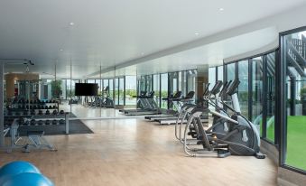 There is a large room with multiple exercise machines and an indoor water park in the center at Avani Sukhumvit Bangkok Hotel