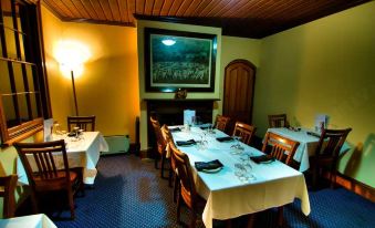 a dining room with a table set for a meal , surrounded by chairs and a fireplace at Poet's Recall Motel