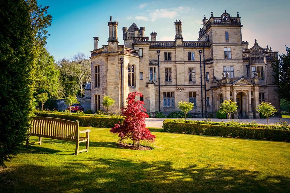a large stone building with a red tree in front of it and a bench in the foreground at Pale Hall Hotel