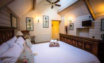 a large bed with a wooden headboard and white linens is in a room with a ceiling fan at The Peak Hotel