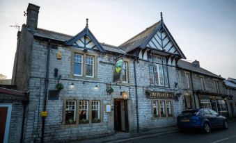"a traditional stone building with multiple windows and a sign reading "" the royal oak "" on the front" at The Peak Hotel