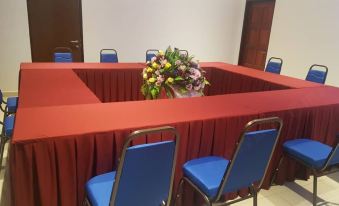 a red dining table with a centerpiece of flowers and candles in the center , surrounded by blue chairs at Star Well Hotel