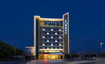 At night, there is a hotel in the foreground with an illuminated building behind it at Lavande Hotel