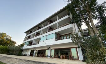 a modern , two - story white building with large windows and balconies , surrounded by trees and grass at Siam Triangle Hotel