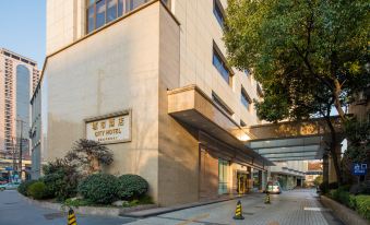The entrance to a hotel in an urban setting features large windows and a stone walkway at City Hotel
