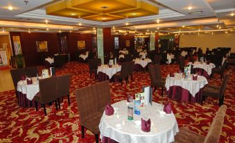 A restaurant is set up with tables and chairs arranged in a formal dining room style for dinner service at Byfond Hotel