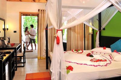 a romantic bedroom with a canopy bed and a man and woman in the background at Vilamendhoo Island Resort & Spa