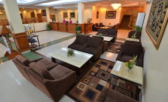 a well - lit hotel lobby with various seating arrangements , including couches , chairs , and other furniture at Grand Palace Hotel