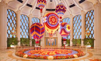 In a spacious room, there are flowers and decorations adorning the ceiling, along with an intricate chandelier suspended above at Wynn Palace