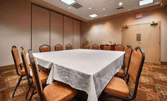 a large conference table with a white tablecloth and chairs in a room with brown walls at Squire Resort at The Grand Canyon, BW Signature Collection