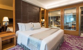 The middle room features a spacious bed, an adjoining sitting area, and a window on one side at Asia International Hotel