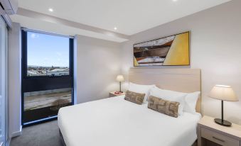 a bedroom with a large bed , white linens , and a view of the ocean through a sliding glass door at IStay Precinct Adelaide