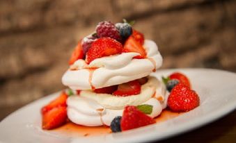 a white plate with a stack of meringue topped with whipped cream , strawberries , and blueberries at Fife Arms Hotel