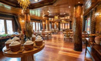 a large dining room with wooden floors and a high ceiling , filled with tables and chairs arranged for a group of people at Khum Wang Nuea Villa