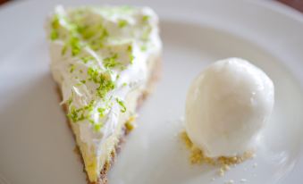 a white plate with a slice of key lime pie topped with whipped cream , sitting on a dining table at The Woolpack Inn