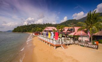 a beachfront restaurant with colorful umbrellas and chairs , situated on a pier near the water at Paya Beach Spa & Dive Resort