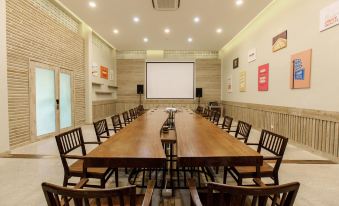 a long dining table surrounded by chairs in a room with brick walls and a projector screen at Lahana Resort Phu Quoc & Spa