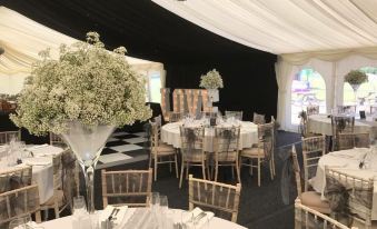 a well - decorated dining room with tables and chairs set up for a wedding reception , with a black and white color scheme at Coach House Hotel