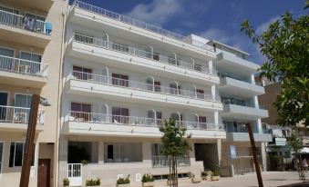 a large white apartment building situated on the side of a street , surrounded by trees at Hotel Cala Bona