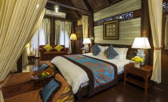 a large bed with a blue and white comforter is in the center of a room with wooden furniture at Zantiis Ndol Villas