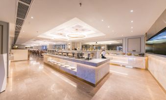 a large , modern restaurant with an open kitchen and dining area , featuring a long marble counter and white marble floors at Hengxing Mercure Hotel