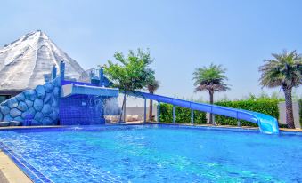 a blue swimming pool surrounded by lush greenery , with a slide leading into the water at Thaiasia Goldensea Resort