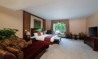 a large bedroom with a king - sized bed , multiple chairs , and a window with curtains , along with a couch and table at Paradise Hotel