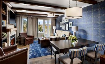 a spacious living room with a blue and white color scheme , featuring a dining area , couch , and fireplace at Fairmont Chateau Whistler