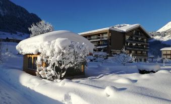 a snow - covered building with a large pile of snow in front , creating a snowy winter scene at Hotel Hubertus - Au Bregenzerwald