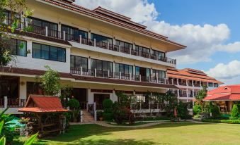 a large , three - story building with red roofs and balconies , surrounded by green grass and trees at Chiangkhan River Mountain Resort