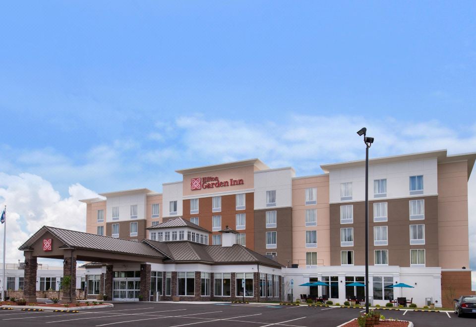 a large , modern hotel building with multiple stories and a parking lot in front of it at Hilton Garden Inn Bristol