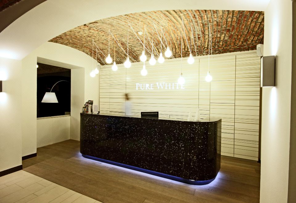 a reception desk with a black counter and a person behind it , under a ceiling made of bamboo at Pure White
