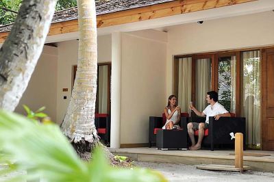 two women sitting on a couch in front of a building , one of them is talking to her at Vilamendhoo Island Resort & Spa