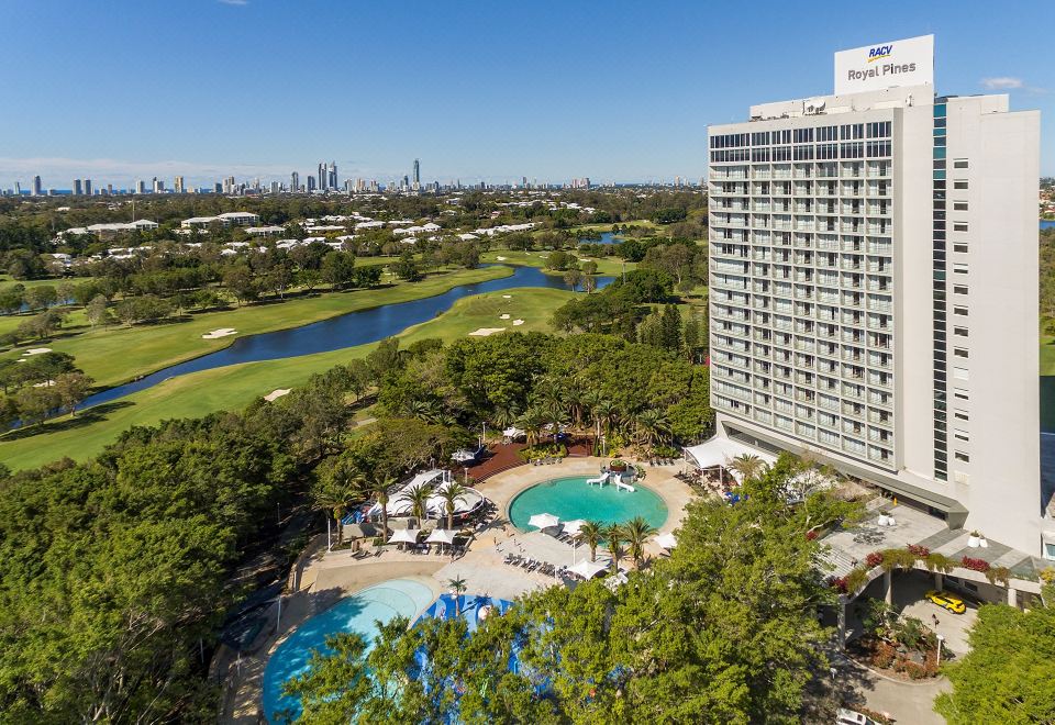 a hotel with a golf course in the background , surrounded by trees and a body of water at Racv Royal Pines Resort Gold Coast