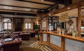 a bar with a wooden counter and shelves filled with bottles , next to leather couches and a checkered floor at Mick O'Sheas