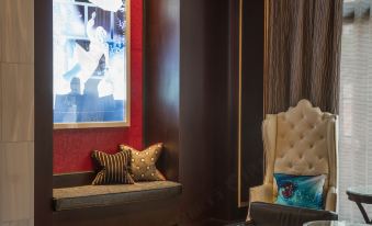 a cozy living room with a large window , a couch , and a dining table , all set against a red wall at Juniper Hotel Cupertino, Curio Collection by Hilton