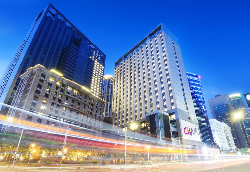 a bustling city street at night , with tall buildings and traffic lights illuminating the scene at Hotel Cham Cham - Taipei