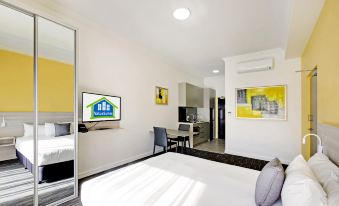 a modern bedroom with a large bed , a desk , and a tv . the room is clean and well - organized at ValueSuites Penrith