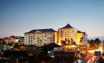 a large hotel building with a tall tower and multiple floors is lit up at night at Melia Purosani Yogyakarta