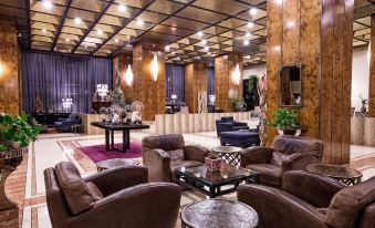 a spacious , well - lit living room with wooden paneling and leather furniture , including couches and chairs at President Hotel
